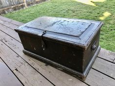 an old trunk sitting on top of a wooden deck in front of a grassy area