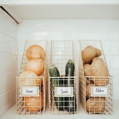 three metal baskets filled with vegetables sitting on top of a white tiled kitchen countertop