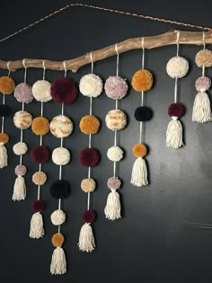 a wall hanging made out of yarn and pom poms on a wooden stick