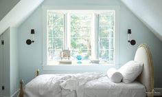 a white bed sitting under a window in a bedroom