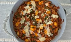 a large pot filled with lots of food on top of a white cloth covered table