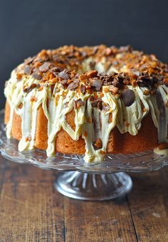 a cake with white frosting and nuts on top sitting on a glass platter