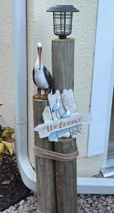 a pelican sitting on top of a wooden post next to a welcome sign