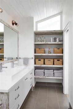 a bathroom with two sinks and open shelvings in it, along with baskets on the wall