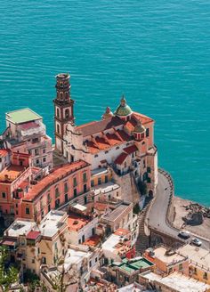 an aerial view of a city by the ocean with buildings and water in the background