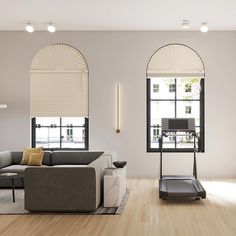 a modern living room with white walls and wood flooring, along with two large arched windows