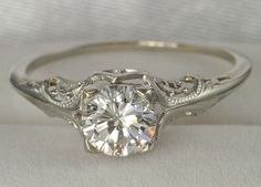 a white gold engagement ring with an old - fashioned style diamond center and filigrees