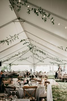 the inside of a tent with tables and chairs set up for an outdoor wedding reception