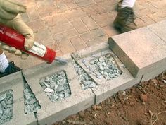 a person with a red and white baseball bat on the ground next to cement blocks