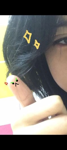 a woman with black hair has two small gold studs on her ear