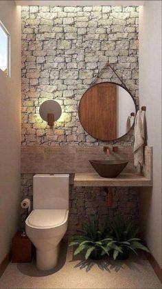 a bathroom with a toilet, sink and mirror on the wall next to a potted plant