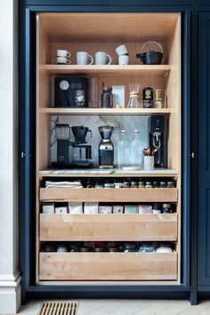 an open cabinet filled with lots of kitchen items and coffee maker on top of it