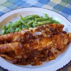 a white plate topped with meat and green beans on top of a checkered table cloth