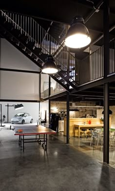 an open room with tables and stairs leading to the second floor that has a car parked in it