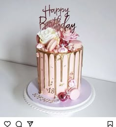 a pink and gold birthday cake with flowers on top