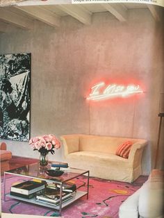 a living room filled with furniture and a neon sign on the wall above it's coffee table