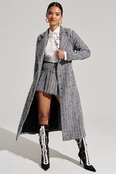 Sophistication at its finest in The AKIRA Label Altura Tweed Trench. This classy outerwear piece is brought to you in a non-stretch tweed base and features a subtle striped contrast patterning throughout, a notch lapel collar, long sleeves with strappy accents and embossed gold metallic button detailing at the cuffs, side slant front pockets, a coordinating tweed waist belt, a sleek inner lining, a back vent slit, and double breasted coordinating front button closures. Complete with a longline silhouette. Pair with the coordinating AKIRA Label Altura Tweed Mini Skirt, a sweater vest, and knee-high stiletto boots for an upscale ensemble. - Main: 100% Polyester, Lining: 100% Polyester- Hand Wash Only- No Stretch- Imported (all measurements approximate from size small)- 47” Shoulder to Hem- 2 Gold Skirt Outfit, Knee High Stiletto Boots, Gold Skirt, Winter Work, Skirts With Boots, Tweed Mini Skirt, Stiletto Boots, Tweed Coat, Winter Outfits For Work