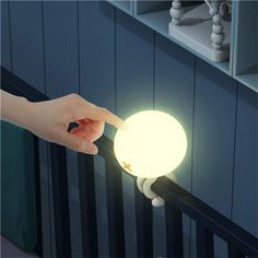 a person is holding a glowing ball in their hand while standing on a stair rail