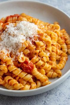 a white bowl filled with pasta covered in sauce and parmesan cheese on top