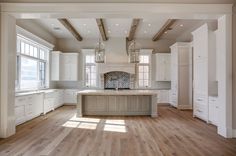 an empty kitchen with white cabinets and wood floors