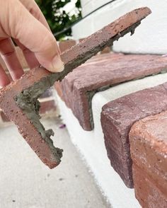 a person is holding a piece of brick