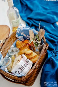 a basket filled with food next to a bottle of wine on top of a table