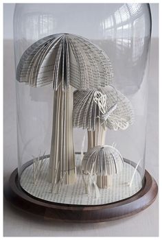 a paper model of two umbrellas under a glass dome on a wooden base,