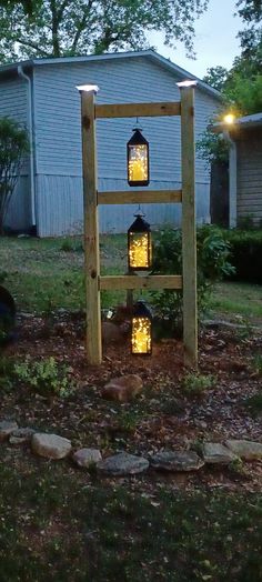 a wooden structure with lanterns on it in the middle of a yard next to a house