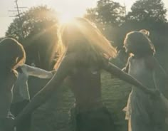 three young women are dancing in the sun