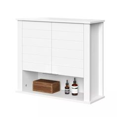 the medicine cabinet is white and has two bottles on it, one with a wooden block