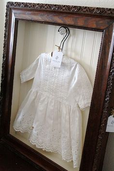 a white dress is in a wooden frame