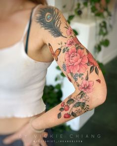 a woman with a flower and feather tattoo on her arm is posing for the camera