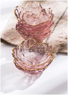 three pink glass bowls sitting on top of a table