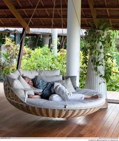 a person laying in a hanging chair on a wooden floor with the words outdoor porch bed above it