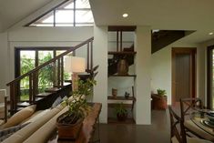 a living room filled with furniture and lots of windows next to a stair casement