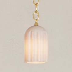 a light that is hanging from a chain on a wall with a white and gold lamp shade