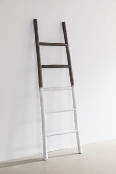 an old wooden ladder leaning against a white wall with no one standing on the floor