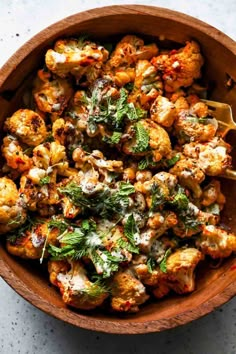 a wooden bowl filled with cauliflower and herbs