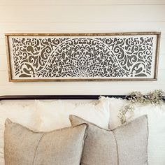 two pillows sitting on top of a bed next to a framed piece of art above the headboard