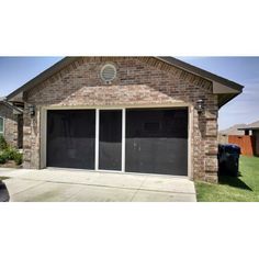 two garage doors are open in front of a brick house