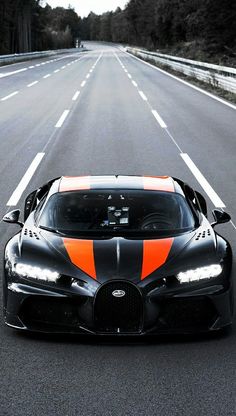 an orange and black bugatti is driving down the road