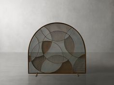 an iron and glass display case with circular designs on the front, sitting on a grey surface