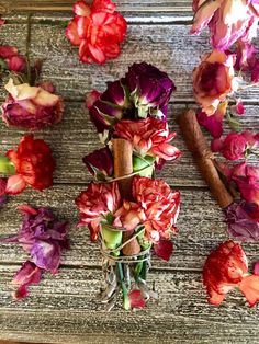 red and purple flowers are arranged on a wooden surface with cinnamons, leaves and sticks