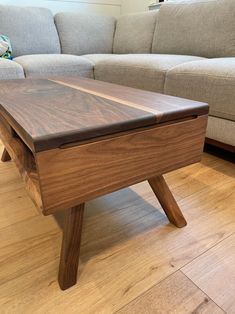 a wooden coffee table sitting on top of a hard wood floor next to a couch