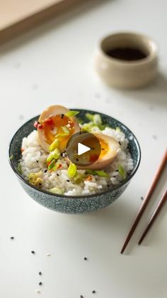 a bowl filled with rice and vegetables next to chopsticks on top of a table