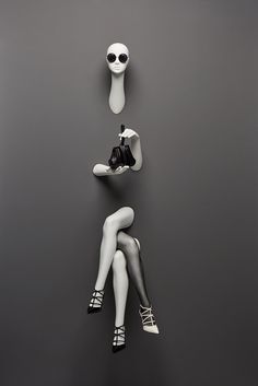 two mannequins sitting next to each other on a gray surface with one woman's legs crossed