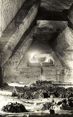 an old black and white photo of people in a tunnel with lights on the ceiling