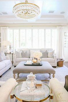 a living room filled with furniture and a chandelier hanging from the ceiling in front of a window