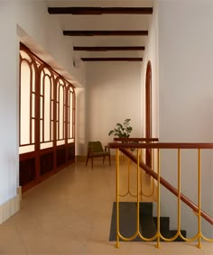 an empty hallway with yellow railings and chairs in the back ground, next to a plant