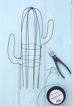 scissors and wire are sitting next to a potted cactus on a blue wooden surface